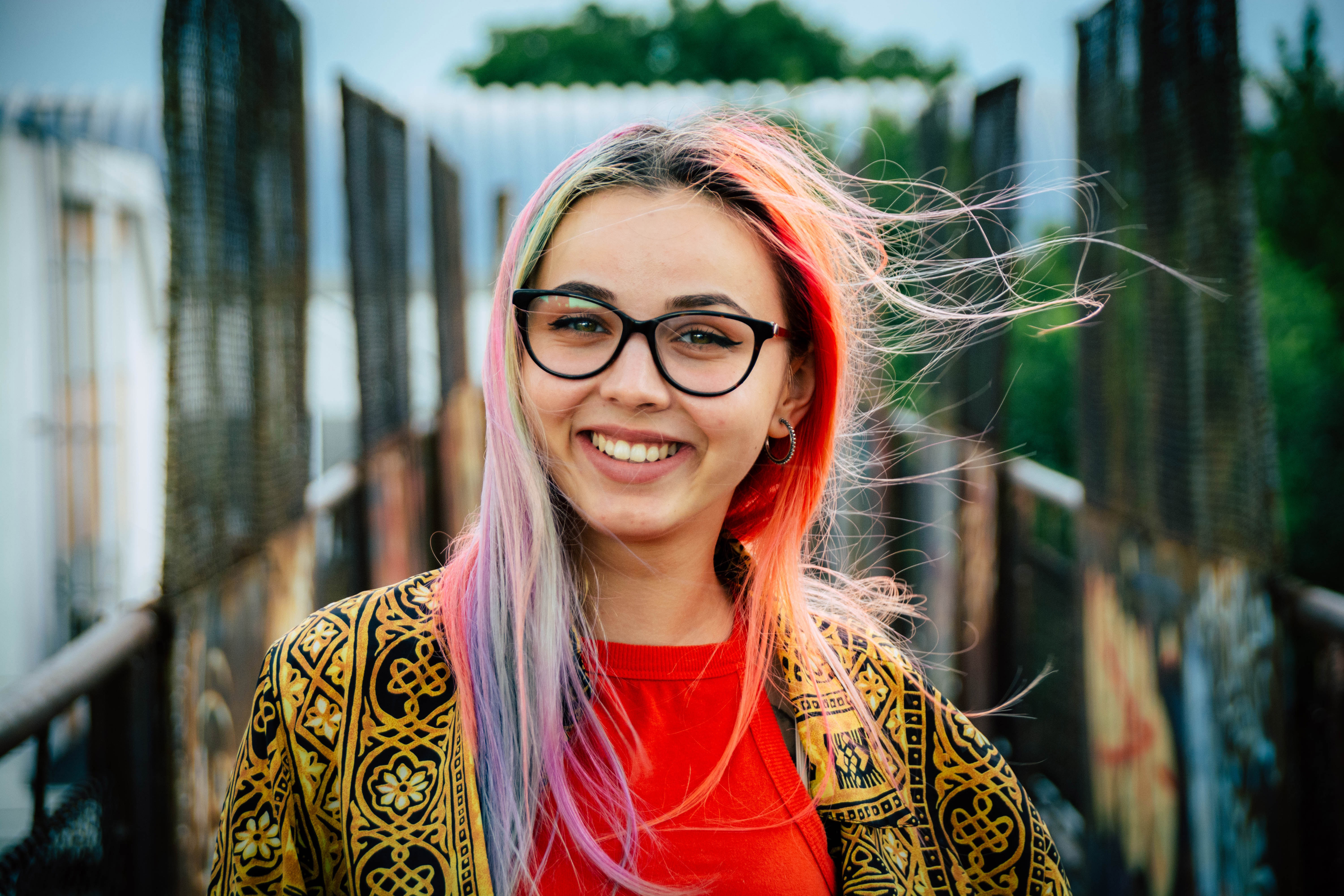 Young woman with glasses and bright multicoloured hair.