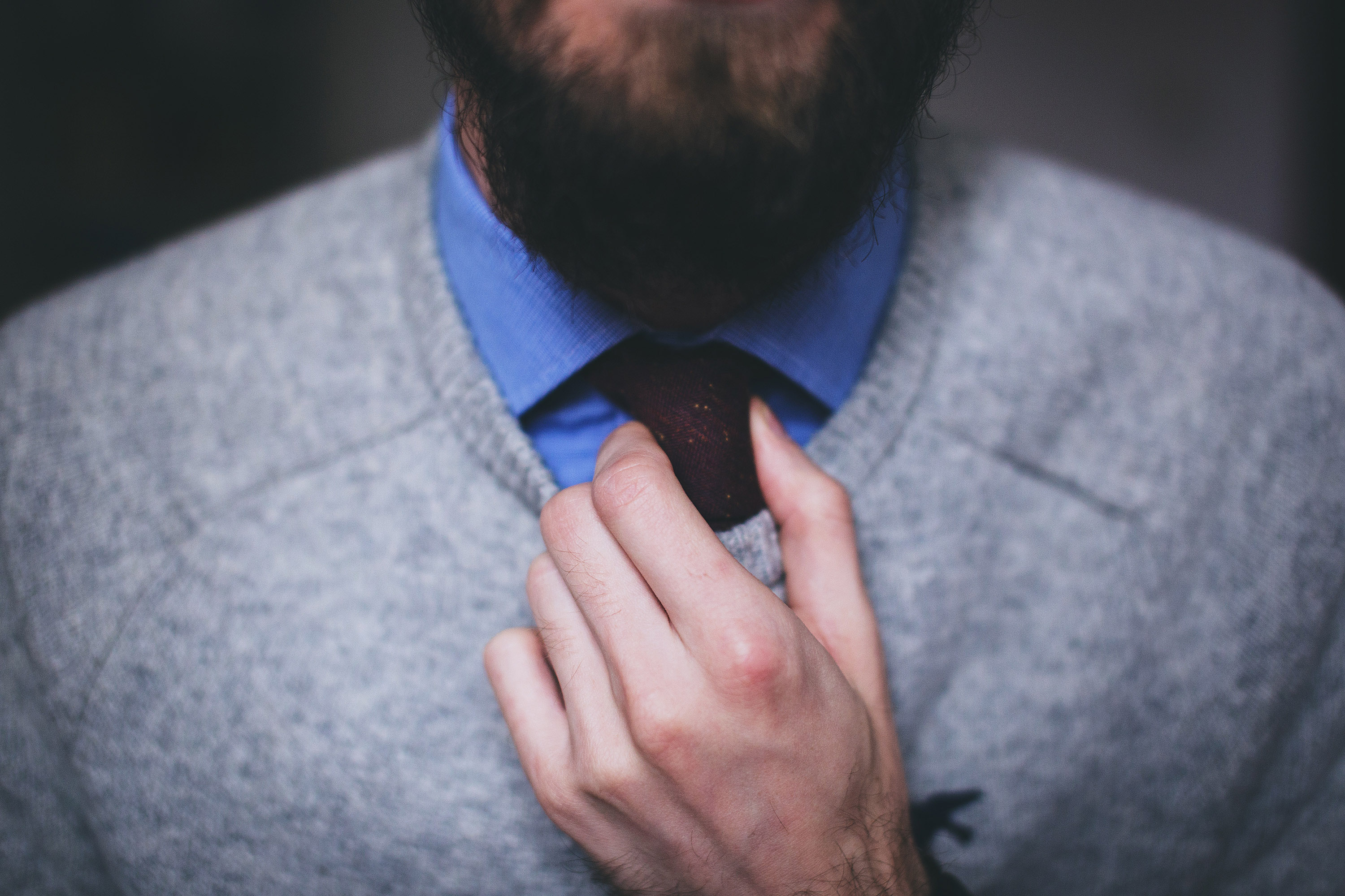 Man wearing professional work attire adjusting his tie.