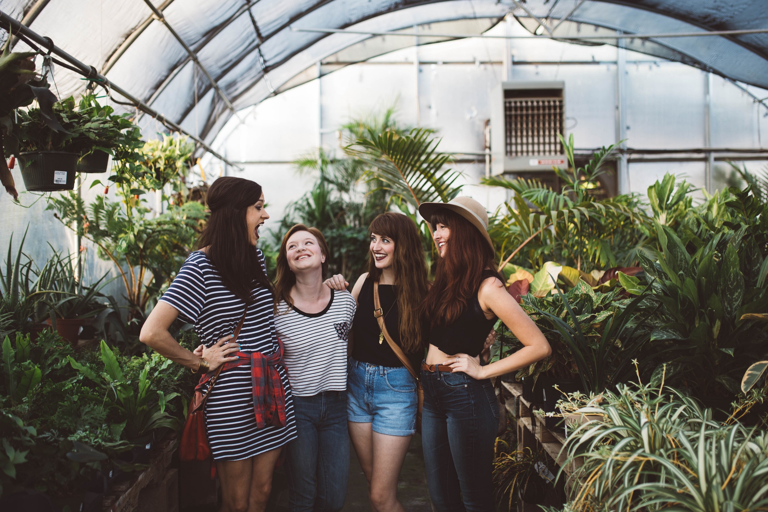 Four women standing together laughing in greenhouse