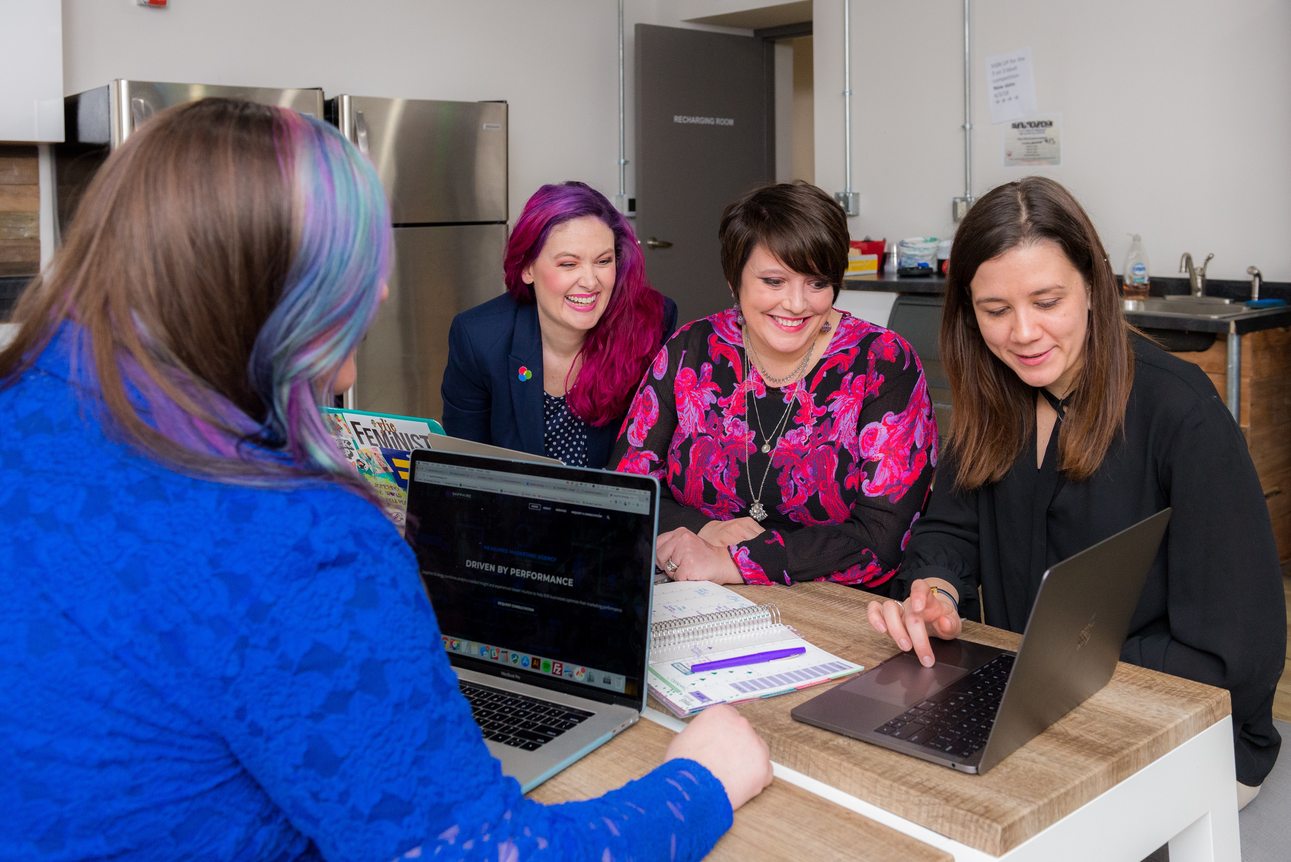 four women meeting in office looking at laptop