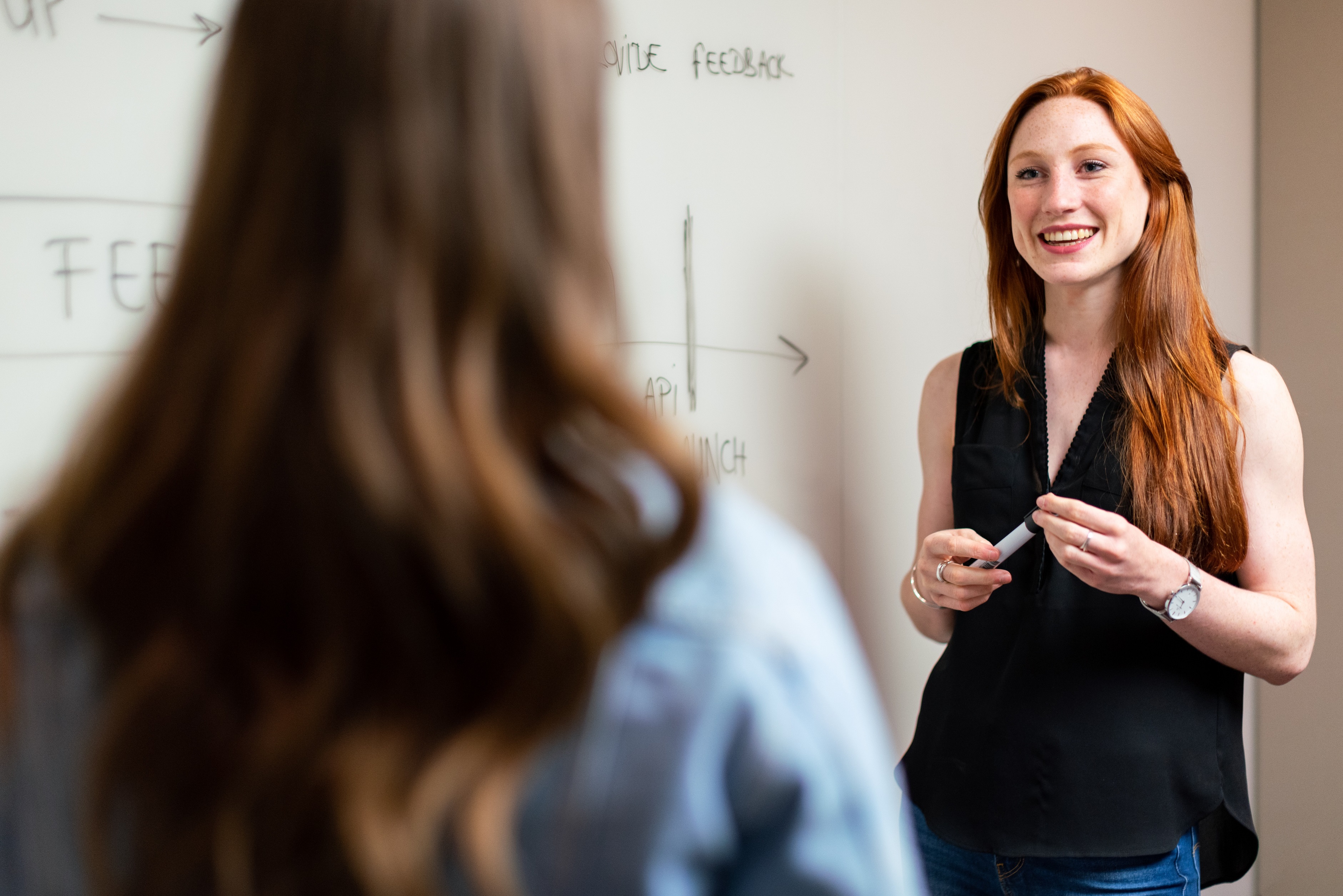 Woman presenting at white board to another woman